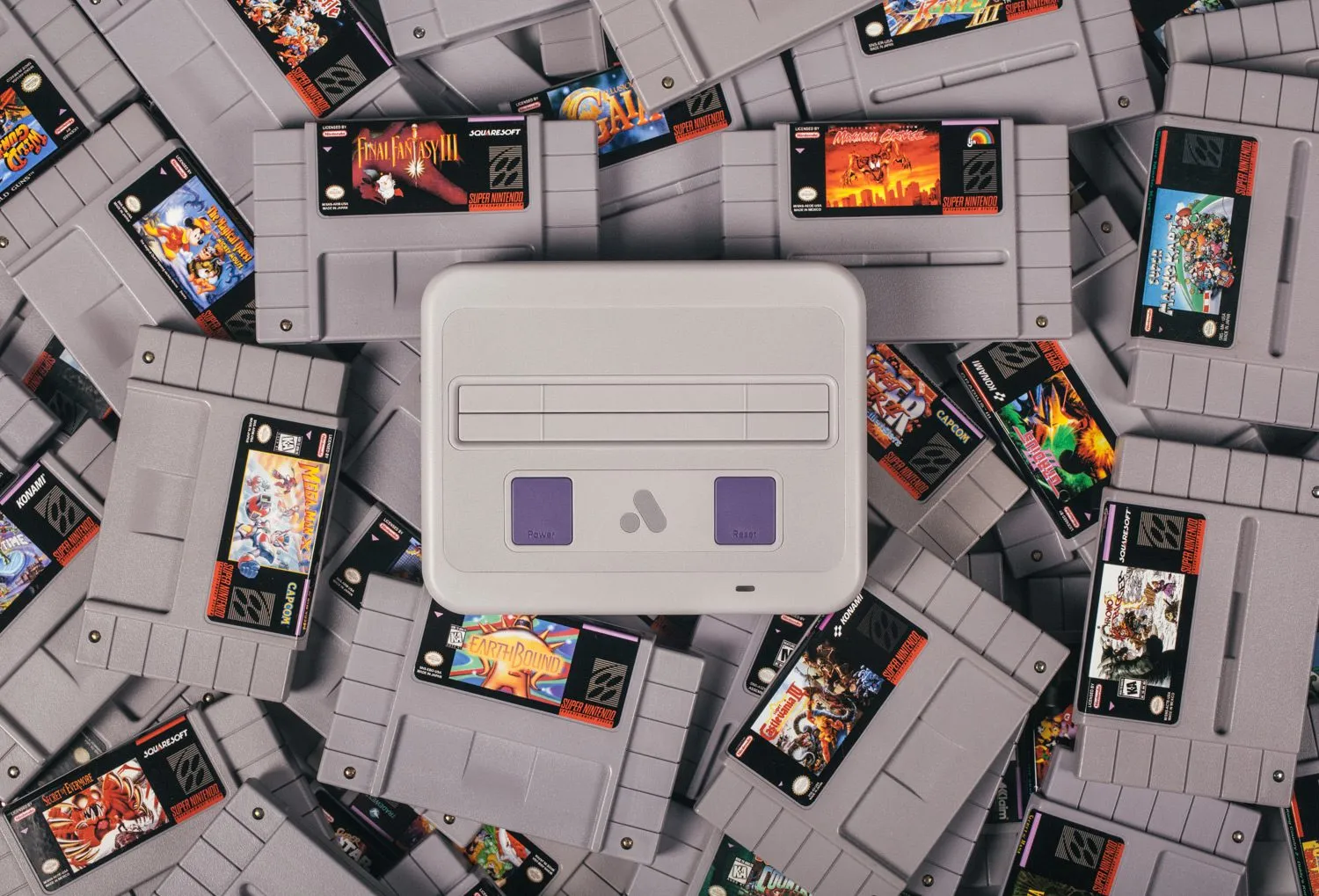 A Super Nt sitting on a pile of SNES carts