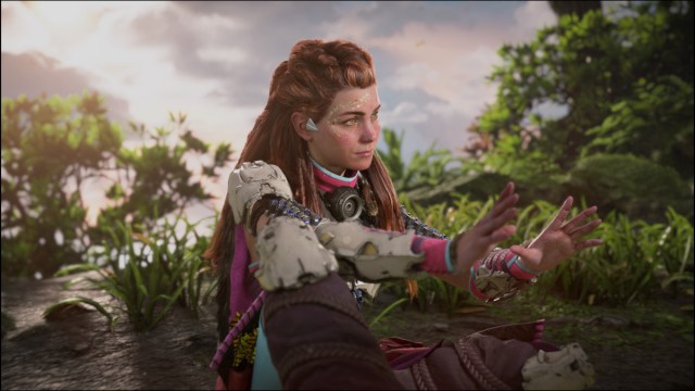Aloy sitting next to fire.
