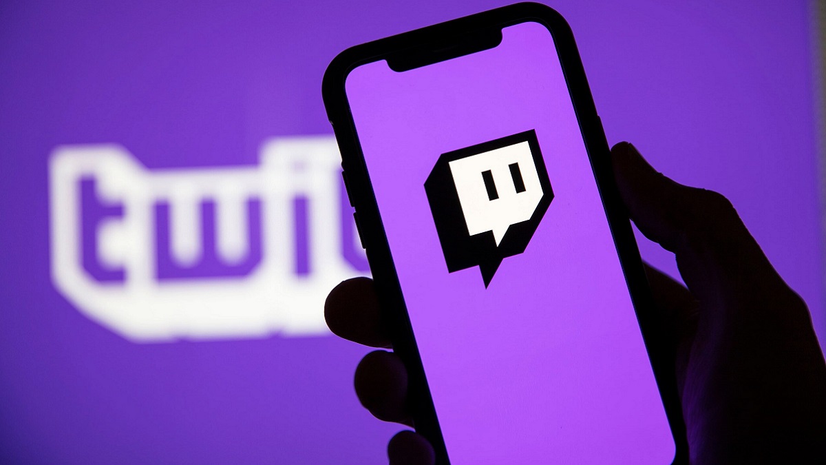 A hand holding a phone with the Twitch logo on.