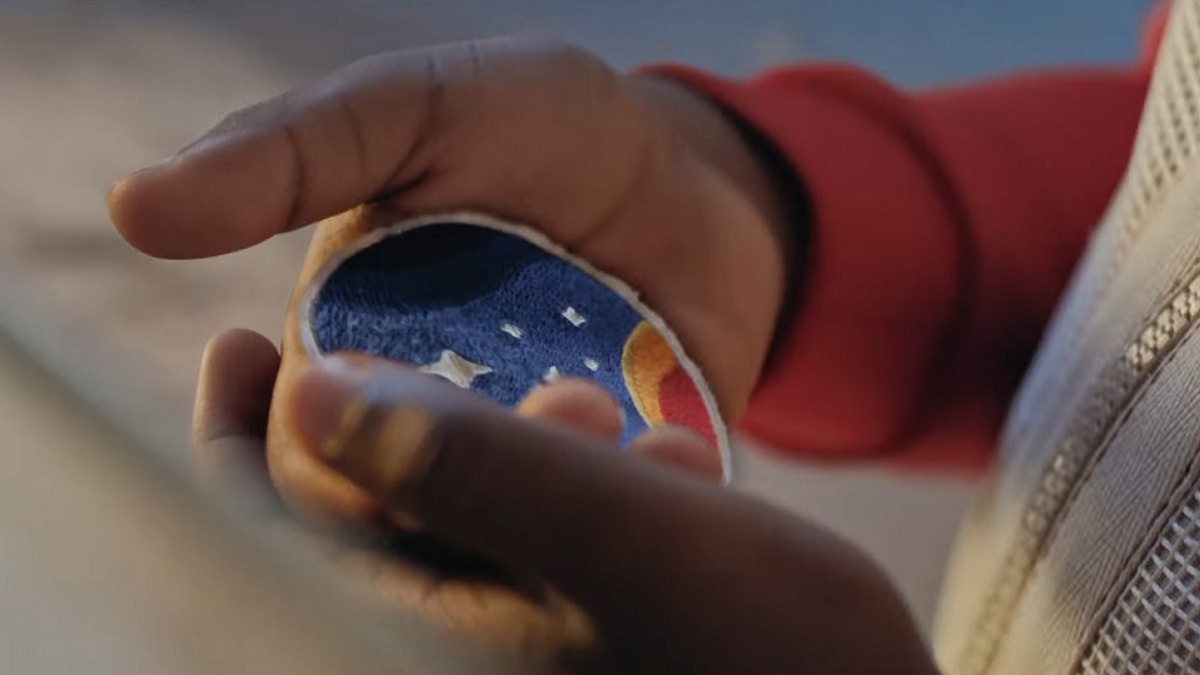 Screenshot from the new Starfield live action trailer showing a hand holding a Starfield badge.