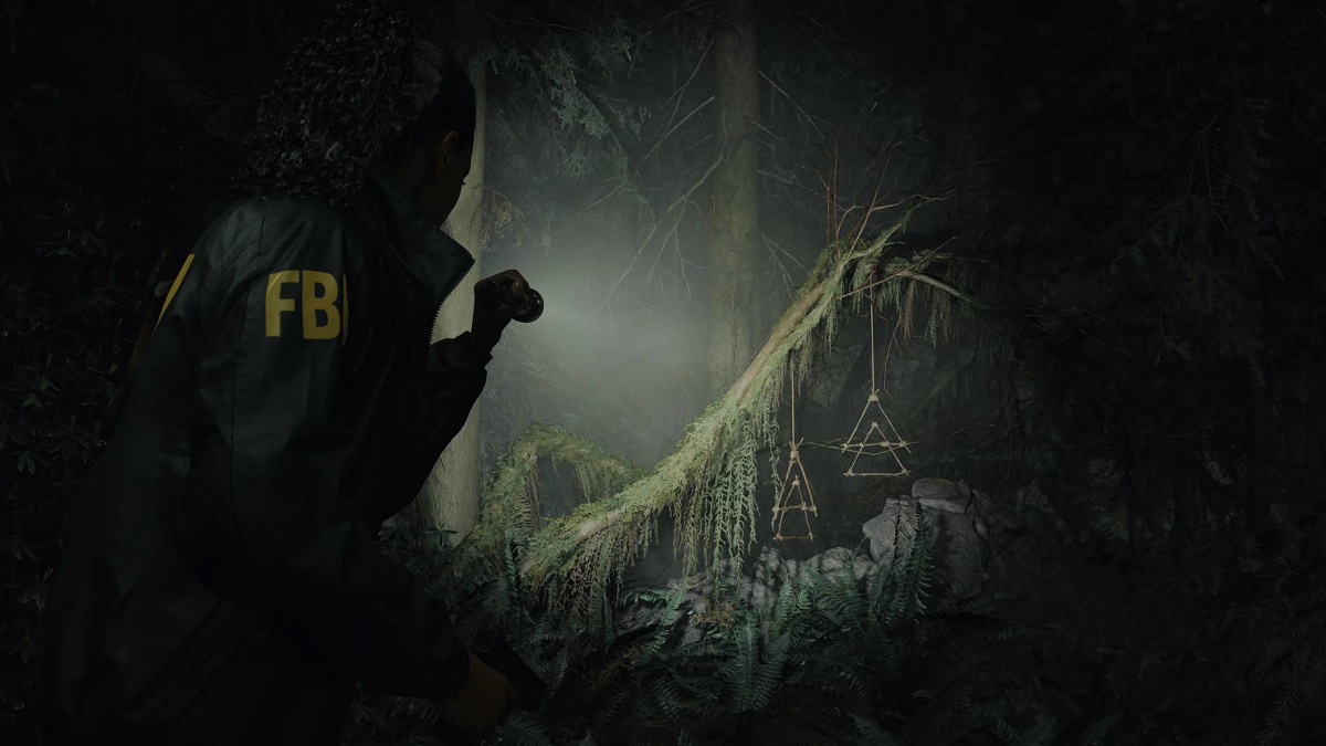 Alan Wake 2: Saga Anderson pointing a flashlight at some trees.