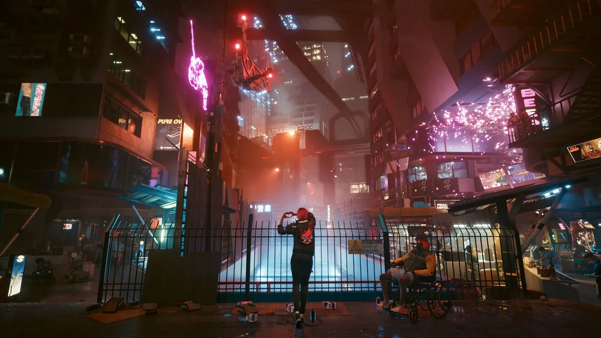 Cyberpunk 2077: a person stands on a bridge and takes in the neon views of Night City.