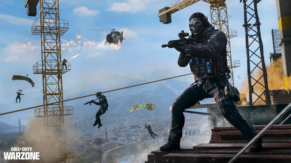 A Warzone player standing on a ledge with a gun as players parachute around him.
