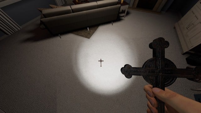 Phasmophobia: a hand holding a crucifix with another one in the middle of a living room floor.