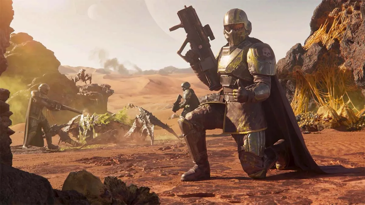 A Helldivers 2 player kneeled down, posing in front of a teammate who is shooting a bug.