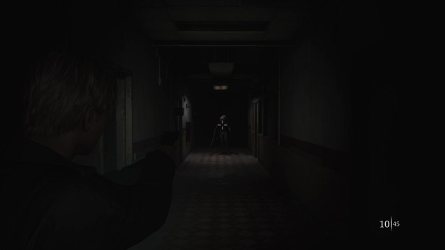Silent Hill 2 Remake - A distant bubble head nurse stands under the light while James aims his gun.