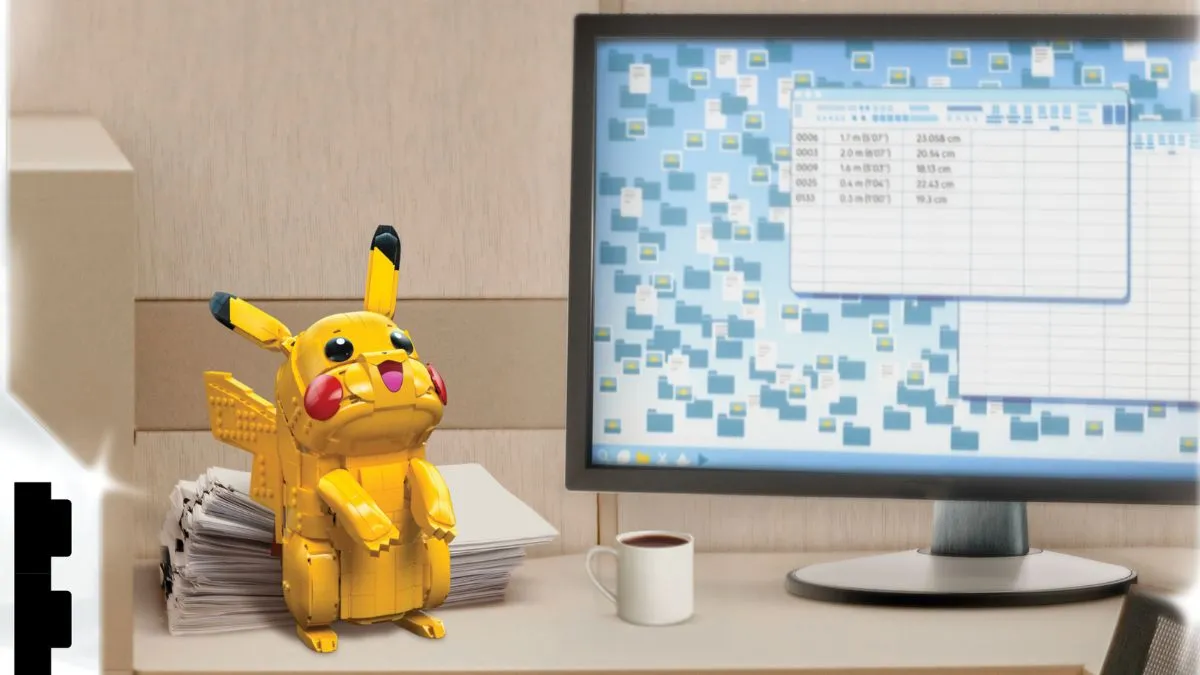 A Lego Pikachu sits on a work desk. On the screen is a spreadsheet showing numbers related to Pokémon categories