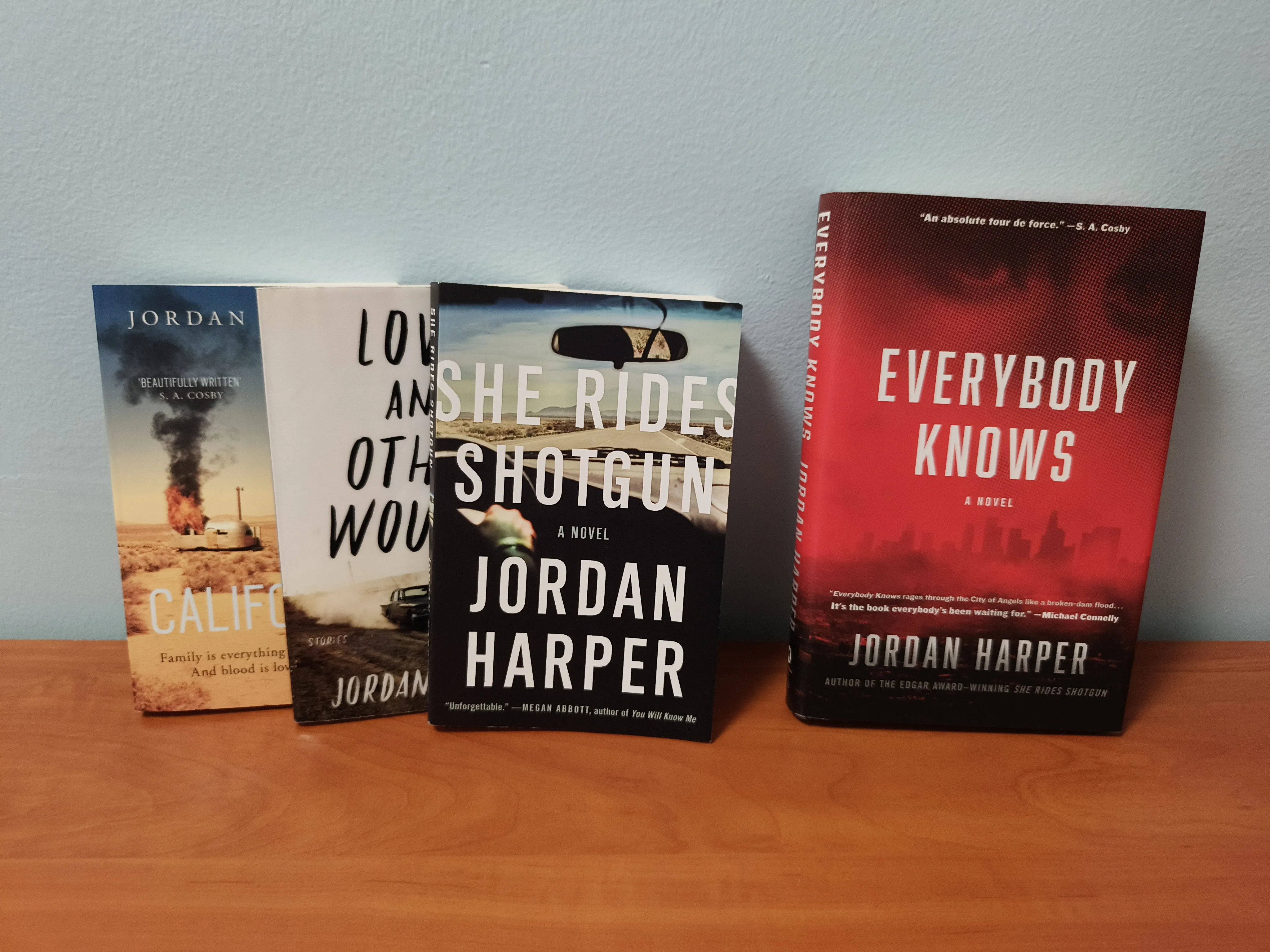 Four books from Jordan Harper stacked up against a wall