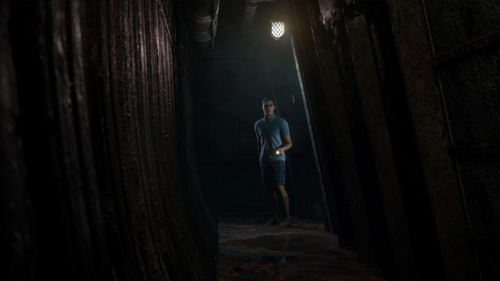 Brad standing in middle of corridor of ship, pointing flashlight