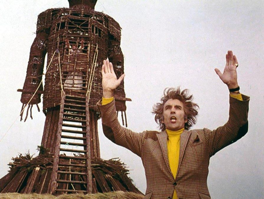 Lord Summerisle with his hands up and the Wicker Man statue behind him